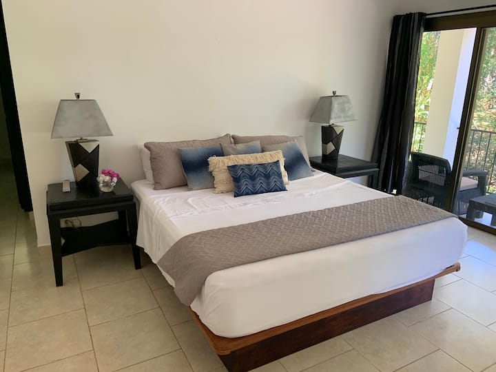 غرفة نوم رئيسية بجانب الحديقة بسرير بحجم كبير وحمام داخلي كامل.