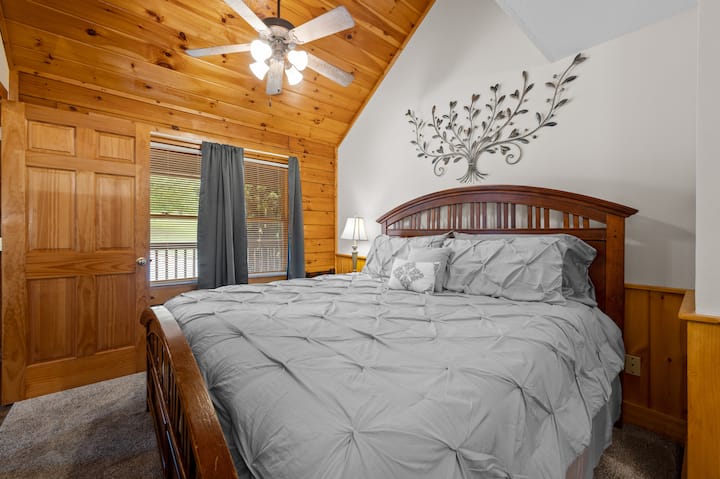 This is a view of the king-sized bed on the main level. This comfortable room comes equipped with blackout shades, a private bathroom entrance, and the laundry machine is located in the restroom off of this bedroom.