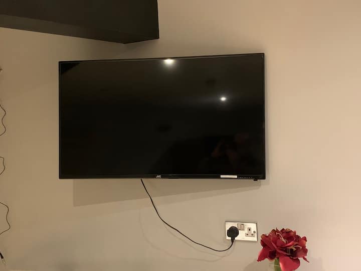 זו טלוויזיה חכמה של JVC, 40 אינץ'. יש בה ערוצי Freeview שונים, כמו גם דברים אחרים. בשל המיקום, יש בעיות בקליטה, לכן ייתכן שיהיה מתאים יותר להשתמש ב-Wi-Fi ולצפות בדברים בטלפון שלכם.