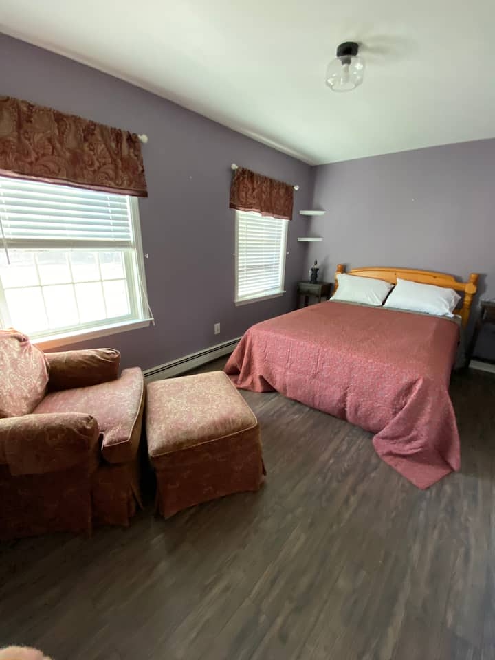 Una cama tamaño queen con tumbona y otomana en el dormitorio de arriba. 