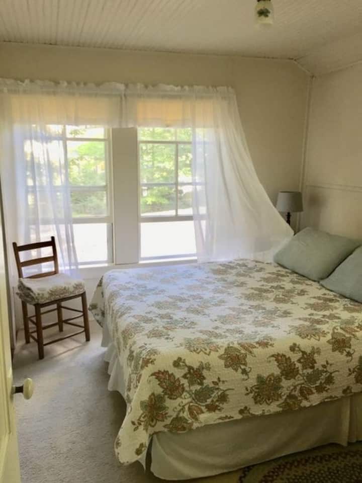 Слатка брачна спална соба на горниот кат исполнета со светлина и воздух има поглед на нашата грижливо згрижена повеќегодишна градина и погон од чакал