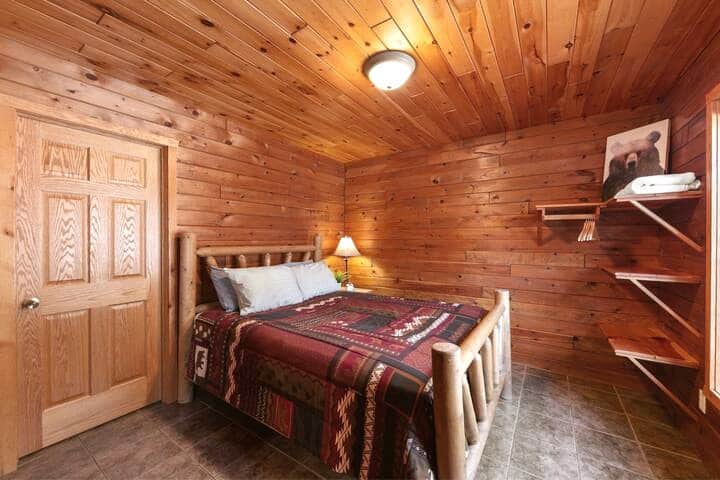 The first bedroom features a queen-sized bed, wood shelving and hanging space, as well as direct access to the shared bathroom through that door!