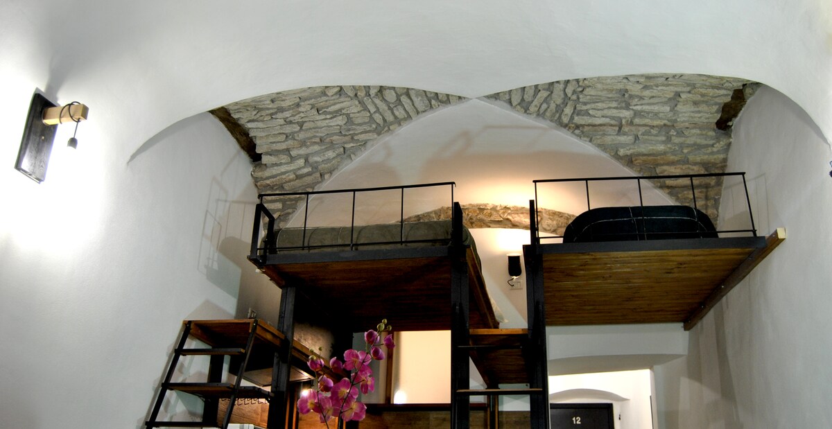 Საძინებელი სივრცე ლოფტია, რომელიც მისაღებ ოთახს გადაჰყურებს.