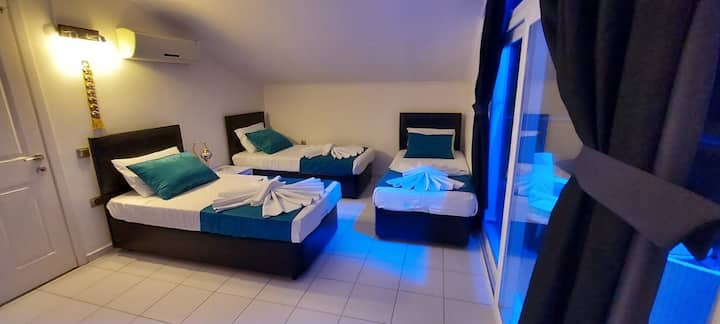 Dhoma e gjumit 4 me 3 krevate tek, hyrje në ballkon dhe banjë familjare.