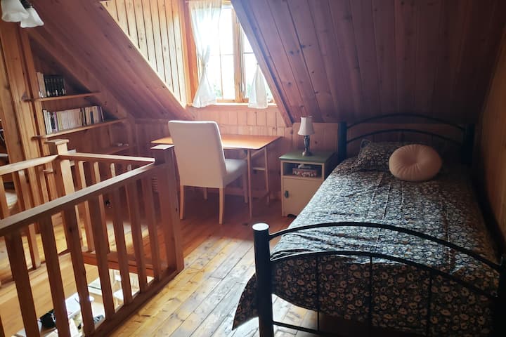 เตียงเดี่ยวและโต๊ะทำงาน 1 ตั้งอยู่ในพื้นที่เปิดโล่งระหว่างห้องนอน 2 ห้องบนชั้น 2