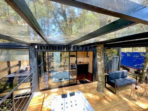 Container in nature with a hot tub and fireplace