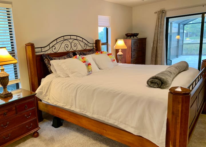 Suite principal con una cama tamaño king, un televisor de pantalla grande y una salida al área de la piscina. 