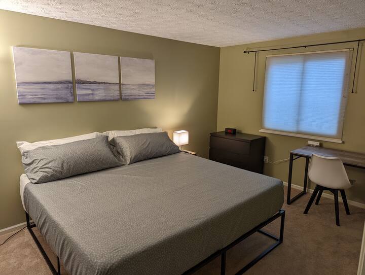 Master bedroom with king size bed, lamp with USB charging ports, alarm clock with USB and wireless charging and desk workstation with power and USB ports.