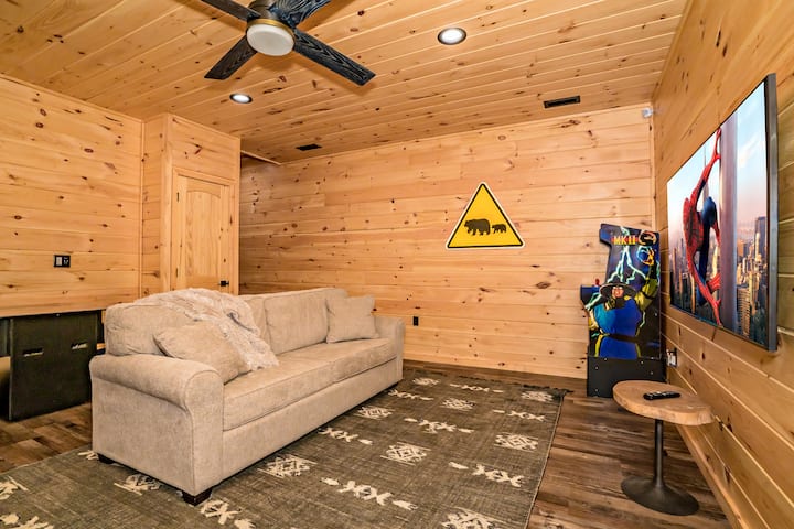 غرفة ألعاب بمستوى منخفض مع أريكة قابلة للسحب ، وتلفزيون ضخم ، وأروقة لمكافحة الفوضى ، وأروقة كوكتيل ، وماكينة كرة الدبوس.