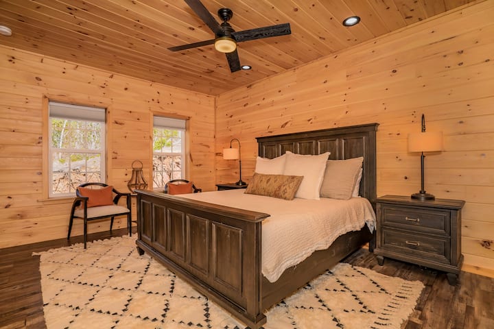 غرفة نوم في الطابق العلوي مع سرير كبير وتلفزيون وحمام رئيسي ملحق