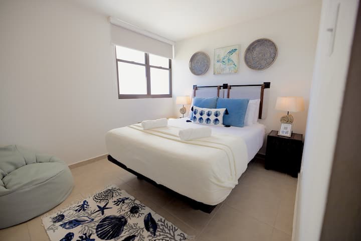 Guest bedroom with queen bed, side tables, lamps and lounge chair