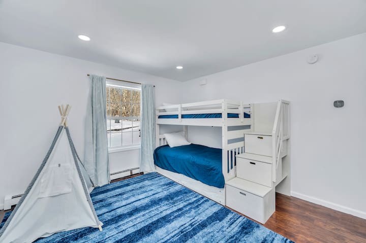 Cozy 3rd Bedroom: Features twin-size bunk beds and darkening curtains for restful sleep. It is kid-friendly, with a selection of books, a play tent, and a kitchen set. Located conveniently across from the bathroom and the second bedroom.