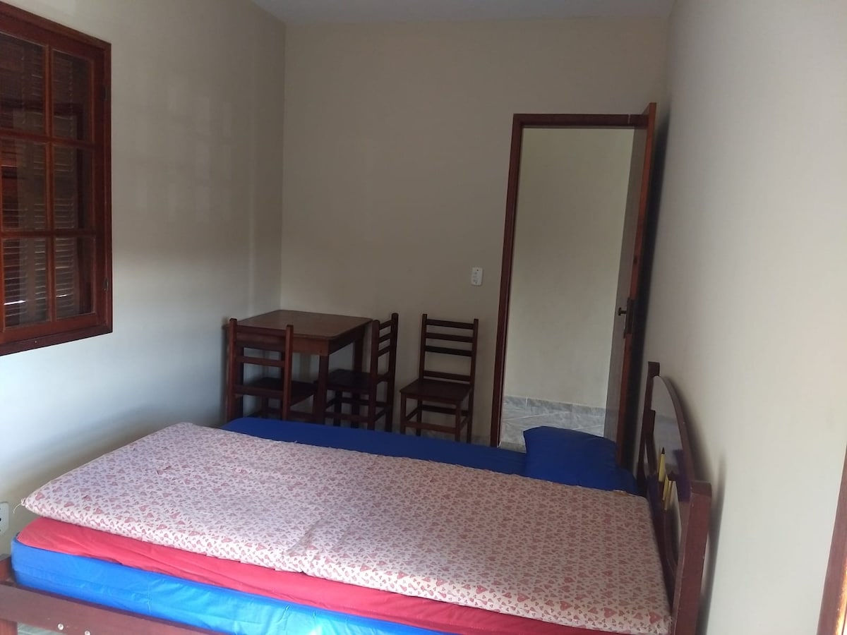 Gornja dvokrevetna soba s bračnim krevetom, policom za knjige, stolom i stolicama, stalkom za odjeću i pufnom.