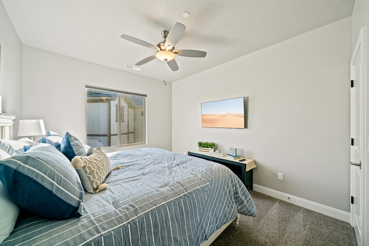 Spavaća soba za goste na katu s madracem na vrhu jastuka, pametnim televizorom i roletnama za zamračivanje. 