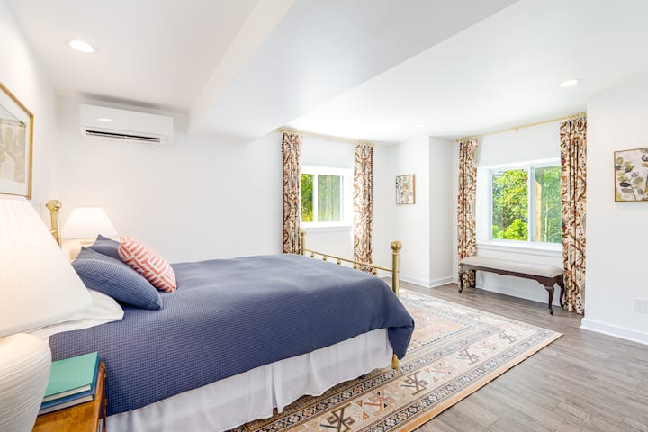 חדר שינה מואר, שליו ואלגנטי עם נוף להרים משני החלונות. 