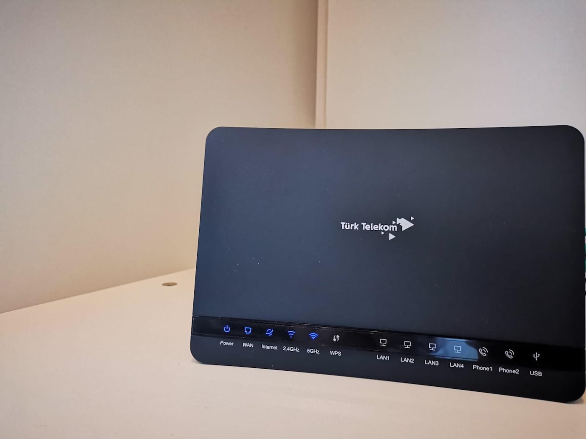 A modern router is placed on a light-colored shelf. The device features a sleek black design with various indicator lights and a logo. The surroundings are minimalistic, highlighting the technology without any distractions.