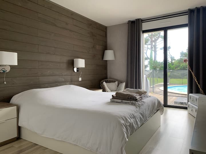 Spálňa #1 hlavná spálňa na prízemí, ktorá čaká na kúpeľňu. Okenné dvere s výhľadom na terasu a bazén 