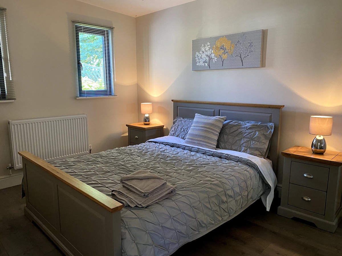 Голема спална соба со брачен кревет и опремени гардероби.