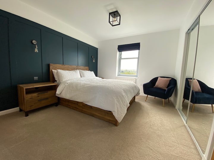 Experience luxury in our master bedroom, outfitted with a comfortable king-size bed, tasteful navy paneling, and the added convenience of an en-suite bathroom.