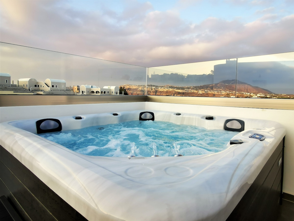 A private hot tub is featured on a spacious terrace, surrounded by a glass railing. The inviting clear water contrasts with the sandy landscape and distant hills, providing a tranquil setting for relaxation.