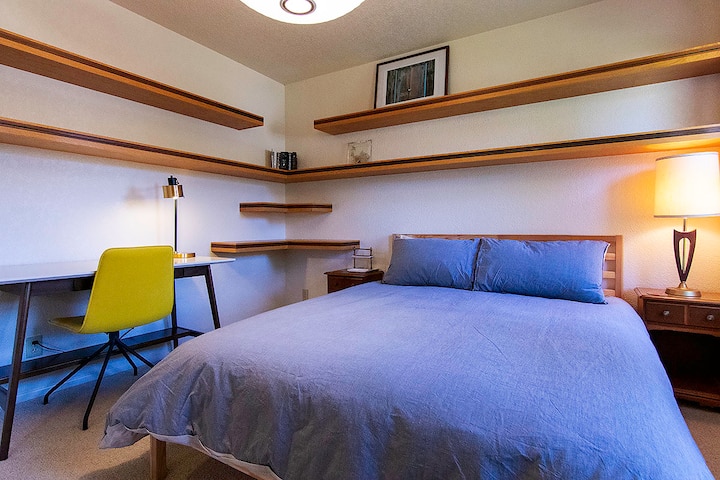 Queen guest bedroom with dedicated working space and bookshelves.  Window faces east.