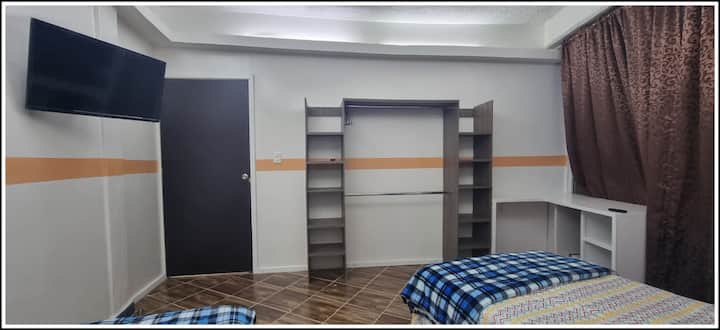 Голема спална соба со два единечни кревета, плакар и биро со жичена интернет конекција, електрични контакти и телевизор со Netflix.