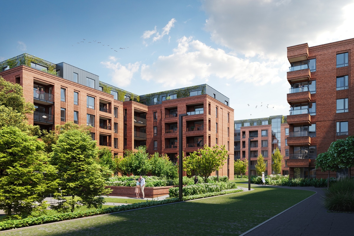 The image captures a modern apartment complex composed of red brick buildings with balconies and green rooftops. Lush greenery and walking paths are visible, creating a park-like setting. A few people can be seen enjoying the outdoor space, enhancing the community atmosphere.