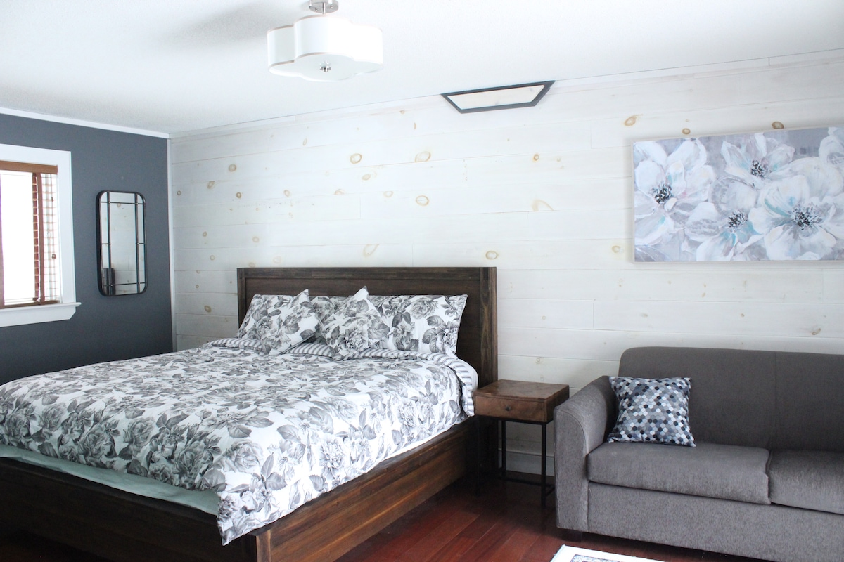 Dormitorio principal con cama tamaño king nueva, sofá cama y baño en suite.