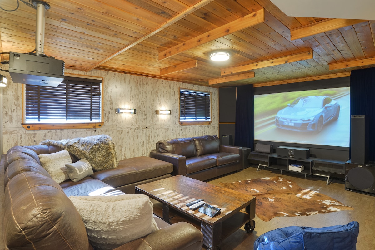 Sala de teatro con proyector, sistema de audio envolvente, sofá cama. 