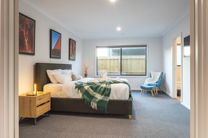 King Master Bedroom ukiwa na Ensuite na uvae vazi. Picha kwenye turubai na mpiga picha maarufu Huber. Taa za kugusa zinazoweza kufifia zilizo na chaji isiyo na waya na kamba nyingi za chaja. Televisheni mahiri ya inchi 40. Kiti cha mkono cha kusoma kilicho na kiti cha miguu. 