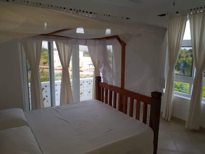 Dormitorio principal con cama «queen size» y balcón