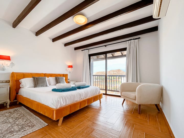 Dormitorio principal en suite con un balcón privado con vistas a las montañas y su propio paseo por el armario.