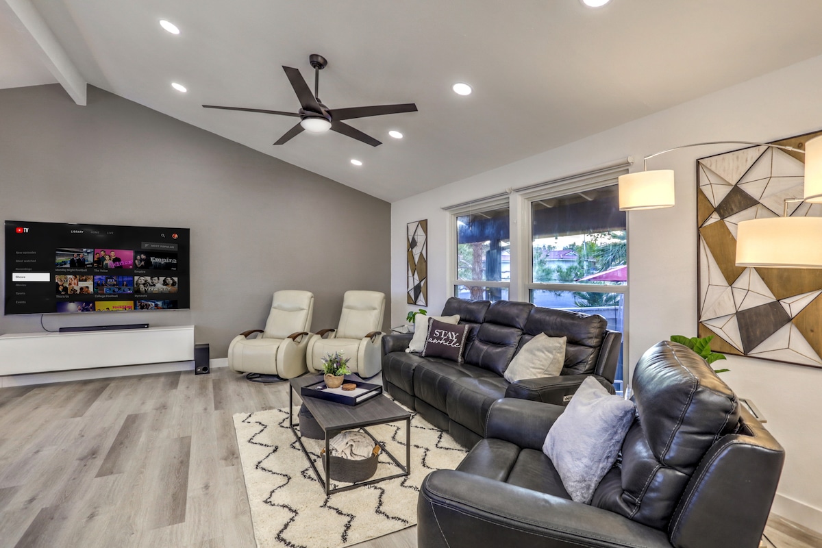 Salón principal equipado con TV inteligente de85pulgadas, sofá reclinable y 3 sillas.