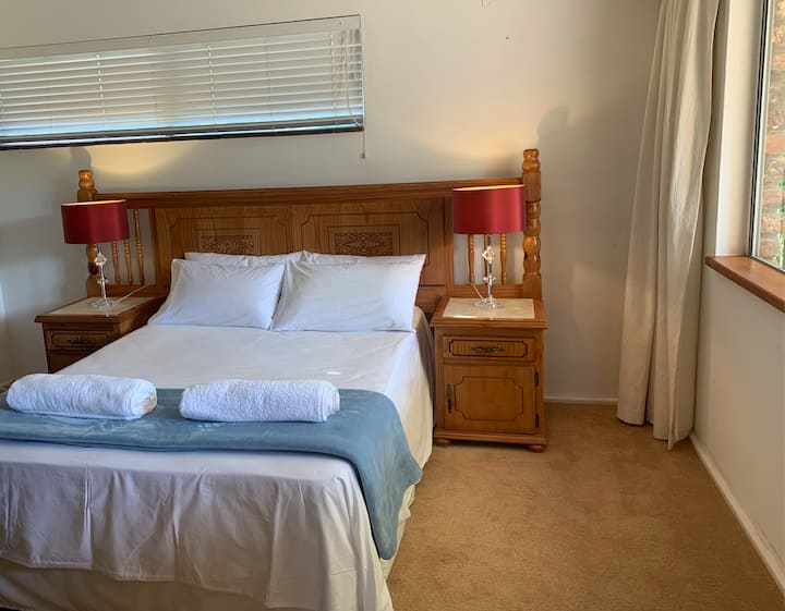 Chumba cha pili cha kulala kilicho na bafu la chumba cha kulala na loo, ukiangalia nje kwenye bustani.