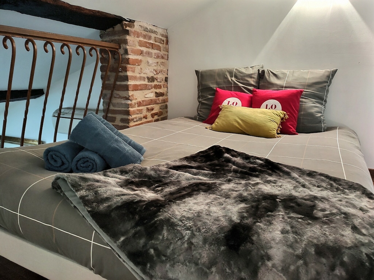 מיטה זוגית הממוקמת בקומת הביניים. החלל פתוח ונגיש מהמדרגות שליד המיטה הראשית