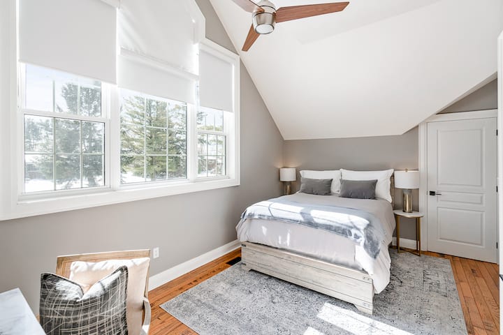 Second level queen bedroom with clean linens, closet, bedside lighting, full size desk, ceiling fan, window covering blinds. NOTE: This bedroom receives the morning sun and the blinds are not 100% blackout. 