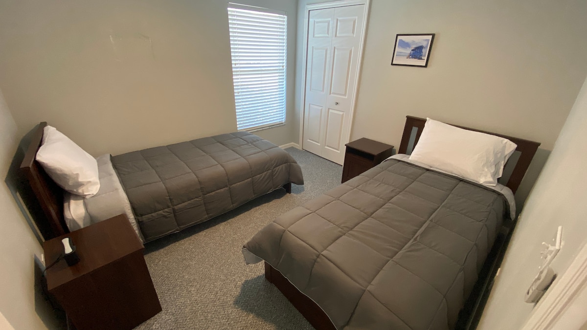 Spálňa pre hostí s dvoma oddelenými posteľami.  Stropný ventilátor.