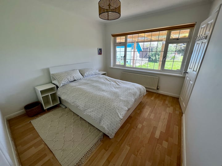 Dormitorio dos con cama doble, almacenamiento y vistas al jardín. 