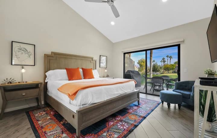 Chumba cha Msingi chenye mandhari ya uwanja wa gofu na kitelezeshi hadi baraza ya nyuma.  Taa zote mbili za meza za pembeni zina pedi ya kuchaji bila waya.