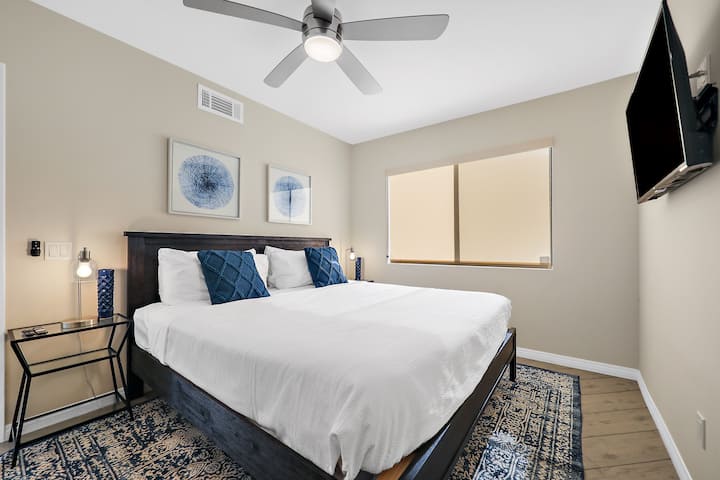 Chumba cha kulala cha pili cha mgeni kilicho na kitanda aina ya king na televisheni mahiri.  Taa za meza za pembeni zilizo na bandari za kuchaji za USB.