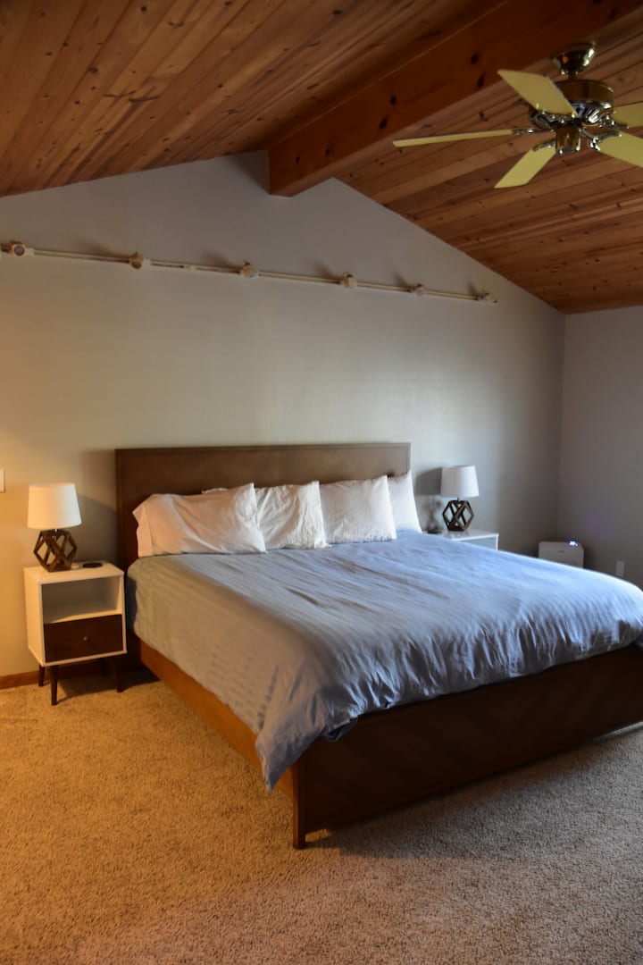 Chumba kikuu cha kulala chenye kitanda na televisheni ya ukubwa wa kifalme.