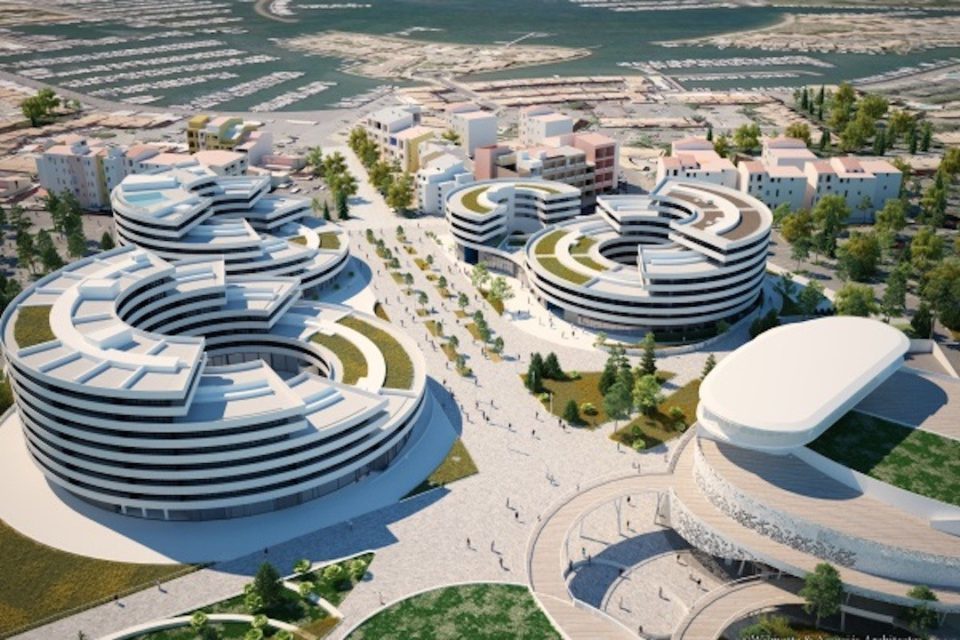 An aerial view captures a modern residential development, showcasing circular buildings with green rooftops. Pathways meander through landscaped areas, while trees and open spaces enhance the pedestrian-friendly environment. The harbor and smaller buildings can be seen in the background, illustrating the vibrant community context.