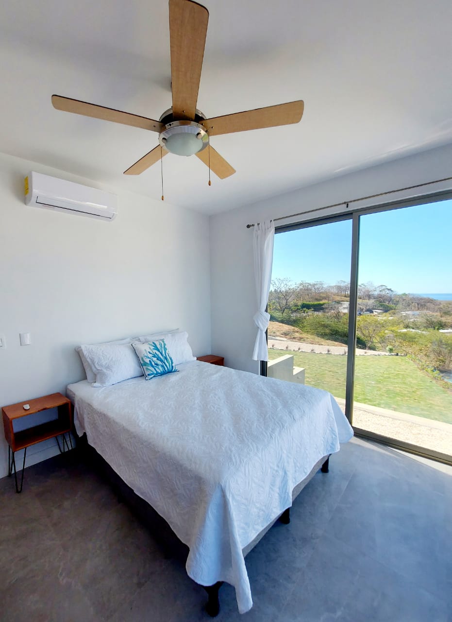 חדר משני עם מיטת קווין סייז ונוף לים.