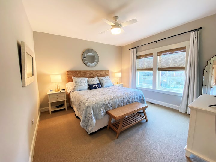 King bed, 2 bedside tables and USB charging capabilities on both sides of the bed. Window shades and black out curtains in space.