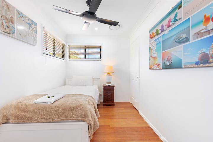 El tercer dormitorio tiene una cama individual tamaño king con una mesa auxiliar y ventilador de techo.
