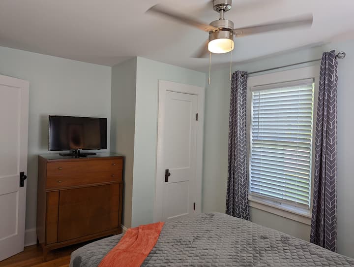 This bedroom is furnished with a queen-sized bed, a 32-inch TV, and one charging station with 3  regular outlets and 4 USB ports. This room has room-darkening curtains.