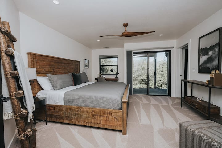 Dormitorio principal en el piso principal con cama tamaño king,  escritorio y baño privado y puertas corredizas de vidrio hacia el área trasera (excelentes vistas al bosque).
