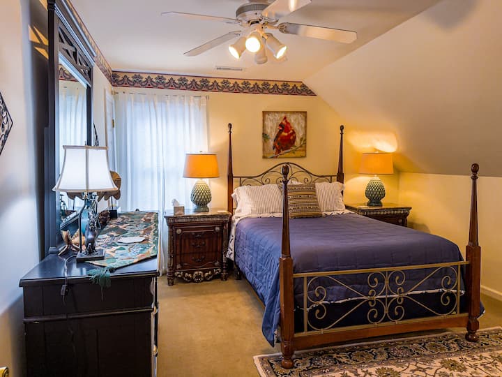 Well appointed bedroom 2 with queen bed, two night stands with lamps, and dresser with mirror and lamp. It has a chair and side table with lamp. This bedroom also has a ceiling fan and walk-in closet. Window faces the pond and cow field side.
