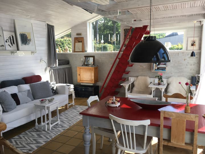 The living room with dining table, sleeping alcove and stairs