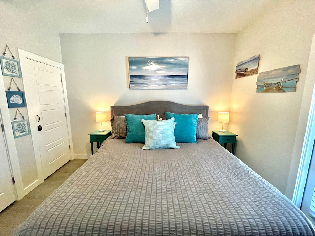 ห้องนอนใหญ่มีเตียงคิงไซส์พัดลมเพดานและทีวีจอแบนพร้อมประตูไปยังลานกลางแจ้งส่วนตัว 